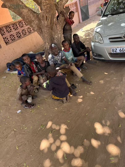 Group of kids sitting by a car outside