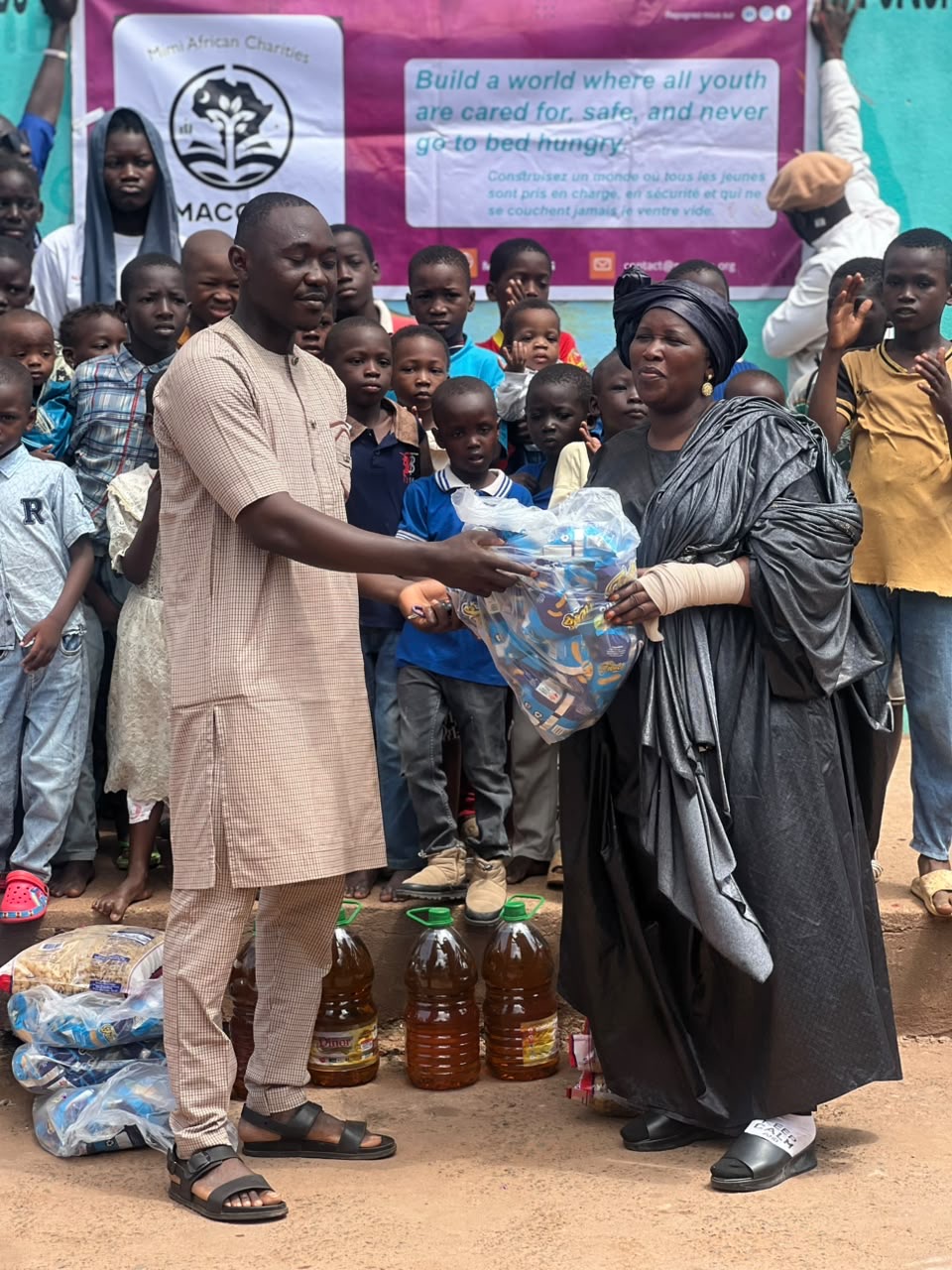 Children clapping as a bag of supplies is passed to the orphanage director in Bamako, Mali